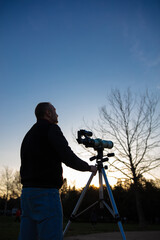 Amateur astronomer observing Sun eclipse and Sun with a telescope and special solar filter.