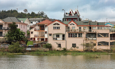 Obraz premium Residential buildings by the lake in a suburb of Antananarivo, Madagascar on a cloudy day