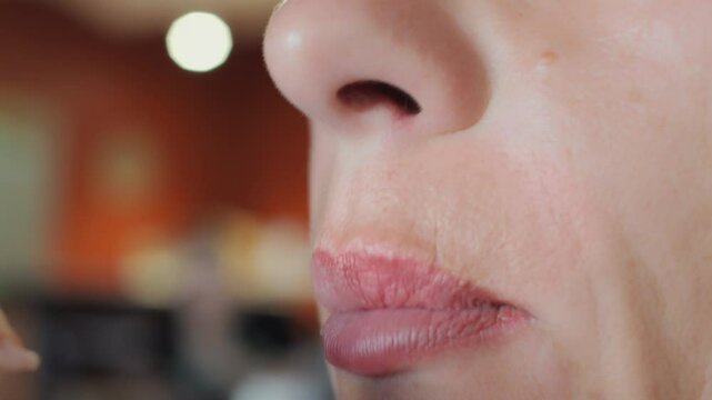 Close-up of lips and mouth of a woman eating pizza in a restaurant. Happy woman putting food in her mouth and chewing.