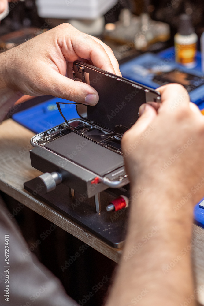 Poster a technician carefully disassembles a smartphone to replace its battery in a well-equipped repair sh