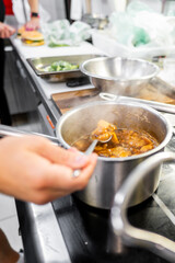 A close-up shot of a person stirring a pot with a ladle in a kitchen. The scene captures the...