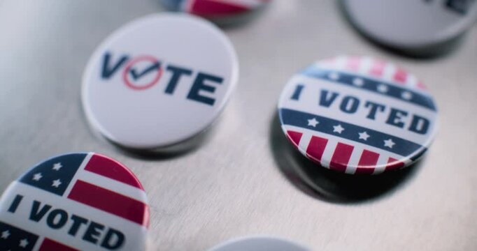 Close up of patriotic badges with American flag logo and inscription. Presidential elections in the United States of America. Political race and election coverage. Democracy and patriotism concept.