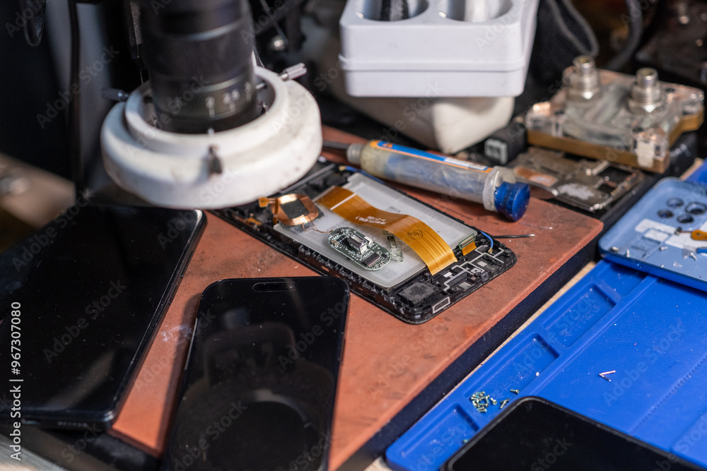 Poster a technician conducts a battery replacement for a mobile phone on a workbench filled with various to