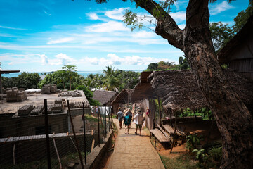 Visitors exploring a vibrant village in Madagascar with traditional huts and tropical scenery during a sunny day