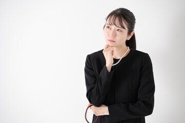 喪服を着た女性　悩む