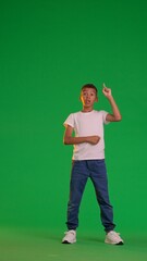 Enthusiastic Schoolboy Pointing Upwards on Green Screen