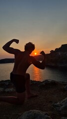 Silhouette of bodybuilder posing at sunrise on the beach