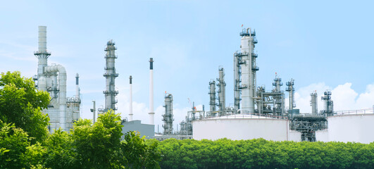Oil refinery plant from industry zone with lush green trees and blue sky, large Oil and gas...