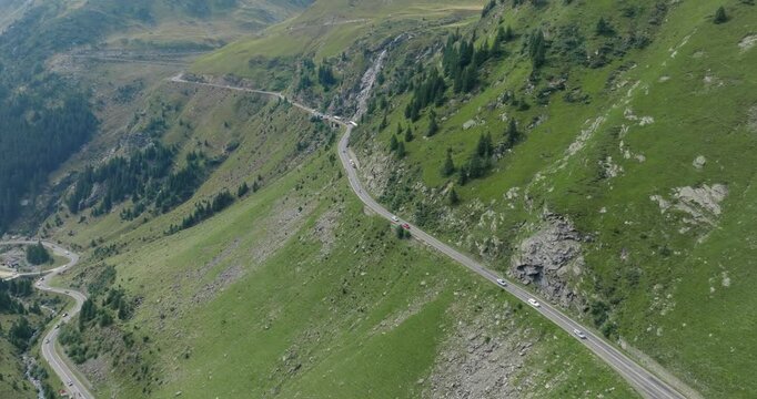 Aeriel Drone View of the Transfagarasan Highway in the Carpathian Mountains of Transylvania in summer with green forest and grass. Winding Road with cars driving in 4K