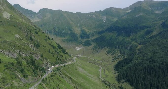 Aeriel Drone View of the Transfagarasan Highway in the Carpathian Mountains of Transylvania in summer with green forest and grass. Winding Road with cars driving in 4K