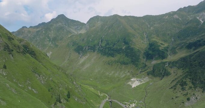 Aeriel Drone View of the Transfagarasan Highway in the Carpathian Mountains of Transylvania in summer with green forest and grass. Winding Road with cars driving in 4K