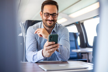 Businessman Traveling on Train Using Smartphone and Laptop