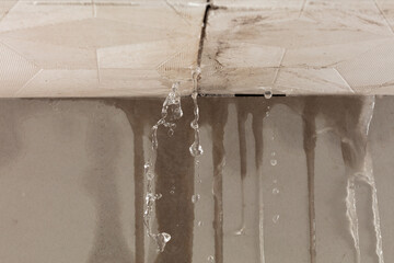 Heavy storm rain create water flow from edge of ceiling and dirty stain on wall. Water leaking from top ceiling as droplets and flow in old house