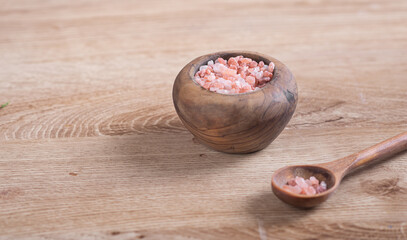 Coarse pink salt in wooden bowl on wooden table