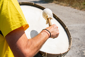 arm of a man in a yellow T-shirt playing a bass drum