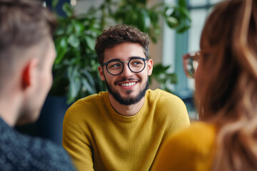 Fototapeta premium Young modern guy wearing eyeglasses and yellow sweatshirt smiling during talking with friends or colleagues. 