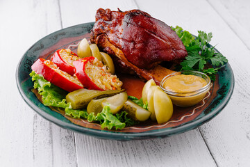 Roasted pork knuckle being served on plate with sauerkraut and mustard