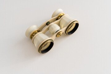 Isometric front view of old fashioned ivory binoculars on white surface. Vintage accessories concept.