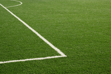 Painted white lines on soccer field with artificial green grass. Outdoors. Summer.