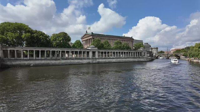 Old National Gallery in Berlin, Germany, Juli 25,2024, time lapse view to the historical building with ship traffic on the Spree river on a sunny summer day