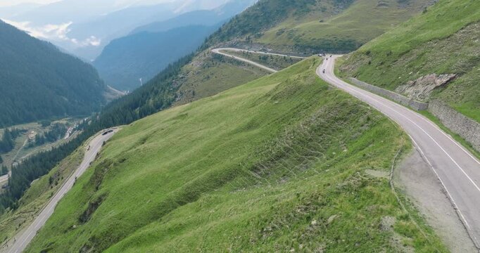 Aeriel Drone View of the Transfagarasan Highway in the Carpathian Mountains of Transylvania in summer with green forest and grass. Winding Road with cars driving in 4K
