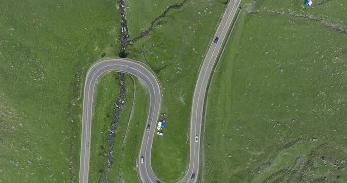 Top Down Aeriel Drone View of the Transfagarasan Highway in the Carpathian Mountains of Transylvania in summer with green grass. Winding Road with cars driving in 4K
