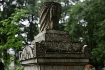 Obraz premium Background shot of ancient sculptured gravestone monument from Victorian era weathered over time and covered with dirt serving as lasting memorial to passed away in rainy graveyard, copy space