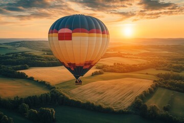 Obraz premium A vibrant hot air balloon floats gracefully above lush fields during sunset. The sky is painted in warm hues and the landscape shines. A perfect moment of tranquility. Generative AI