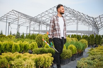 Male employee of garden shopping center inspects product. Department with potted plants, is...