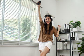 Young Woman Enjoying Music with Headphones and Smartphone in Modern Home Office Environment