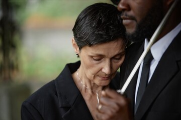 Portrait of sorrowful senior woman grieving over loss of loved one leaning on comforting man during...