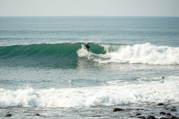 Surfer riding a wave along the rocky coast