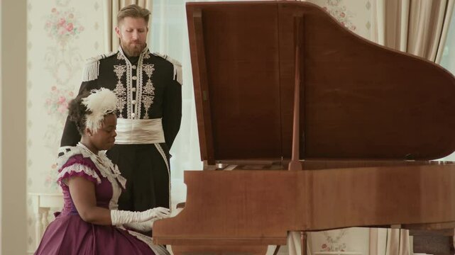 African American woman in purple Victorian-style dress playing grand piano while Caucasian man in black and white ornate military uniform standing behind her in elegantly decorated room