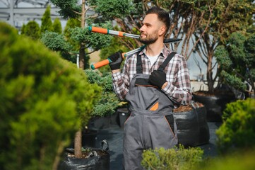 Garden worker trimming trees with scissors. garden shop