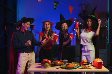 Dinner and group of people celebrating together at Halloween party. Friends are happy and celebrating with food, wine and friendship of love and cheers of champagne at the event.