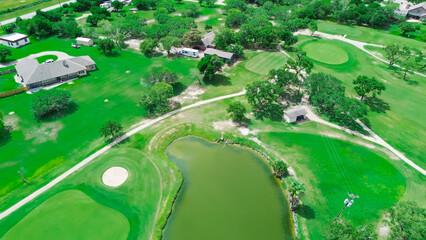 Sand trap and pond in country golf course near Hazel Park, Corpus Christi, South Texas, surrounding residential neighborhood upscale houses with swimming pool, grassy backyard, tall trees, aerial