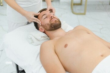 Handsome middle-aged man enjoying relaxing spa massage with oils