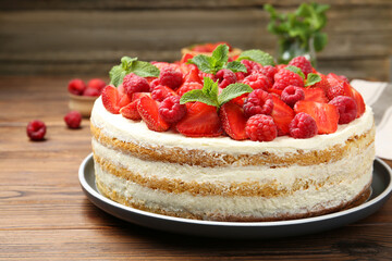Tasty sponge cake with fresh berries and mint on wooden table, closeup