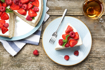 Tasty sponge cake with fresh berries and mint served on wooden table, flat lay