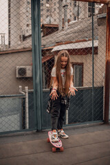 Teenage girl with long blonde hair playing in the city with a skateboard