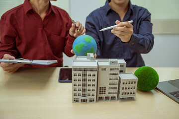 Two businessmen work at desks in an office,discussing city clean energy strategies global...