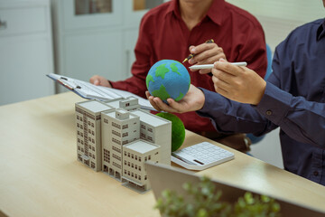 Two businessmen work at desks in an office,discussing city clean energy strategies global...