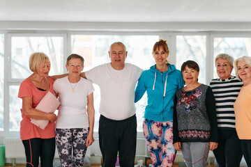 A group of seniors and one man happily pose with their yoga instructor after a successful training session.