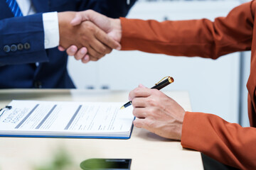  A businessman at a desk in a sales office sells a condo building to a customer. They agree to sign a contract, covering real estate investments in offices, apartments, and commercial properties.