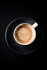 Cup of coffee on dark paper background. Close up. Copy space.
