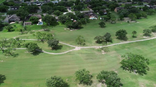 Suburban houses with swimming pool in upscale golf course residential neighborhood Hazel Park, Corpus Christi, Texas, country club sand trap, club cars pathway, grassy fairway, tall mature trees