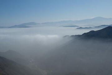 The sky is blue and the mountains are covered in fog