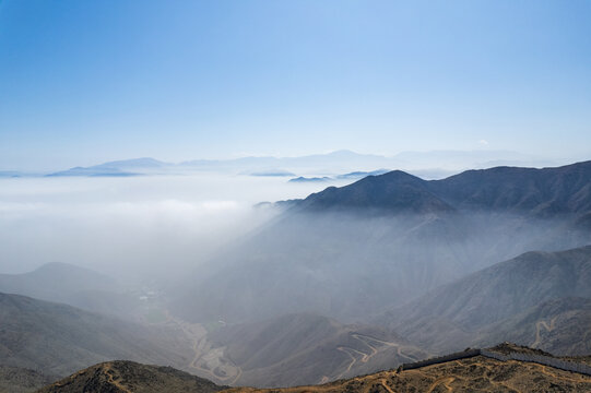 The sky is blue and the mountains are covered in fog