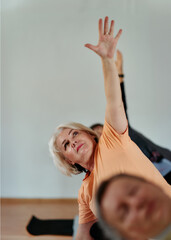Fototapeta premium Senior Women Embrace Wellness: Yoga and Stretching in a Sunlit Space