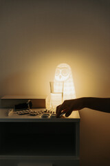 A person's hand grabs medication from a table at night.
